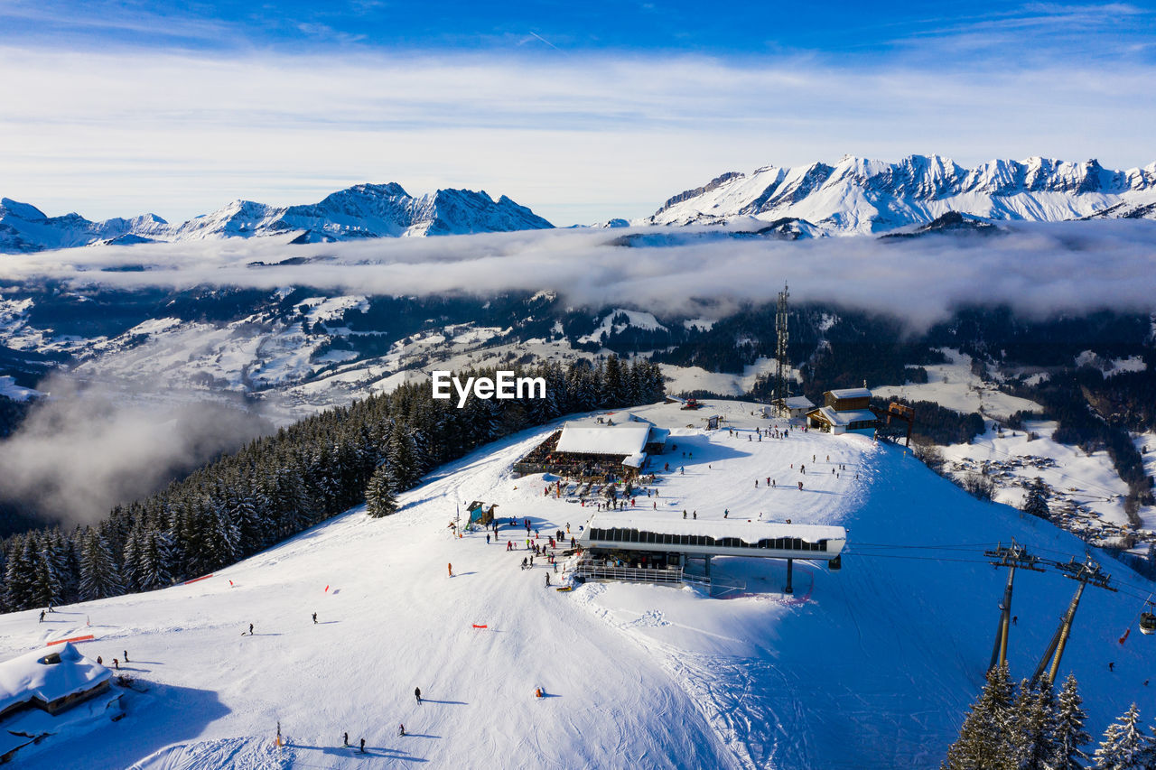 Aerial view of people skiing on snow covered mountain against sky