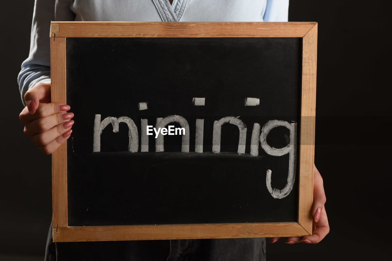 Person holding a sign with the word mining on it