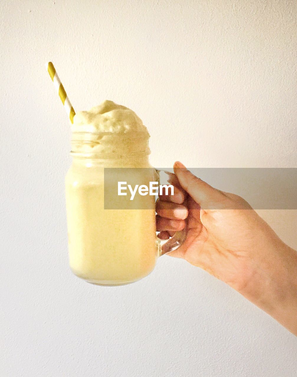 CLOSE-UP OF HAND HOLDING DRINK ON TABLE