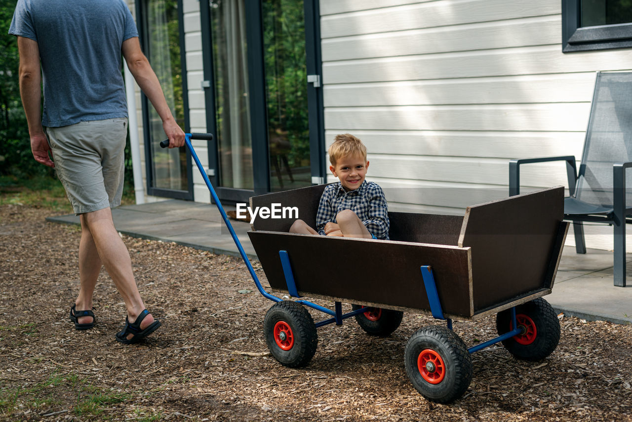 A man pulling a wooden wagon with his son.