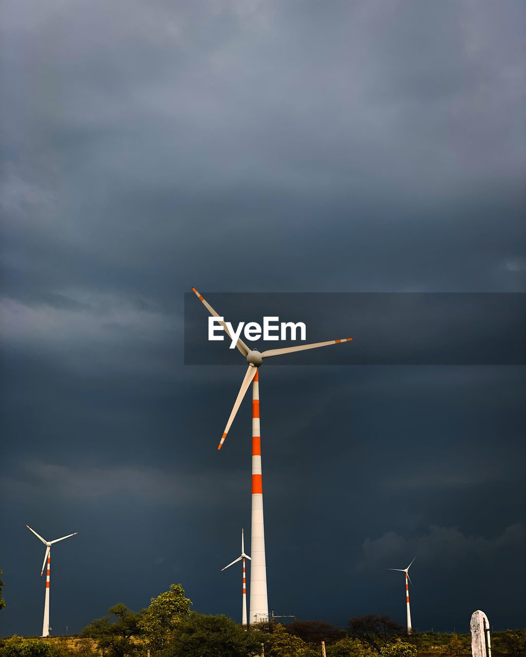 Low angle view of windmills against cloudy sky