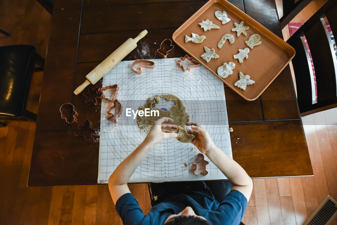 Overhead shot of child's making cookies with cookie cutters.