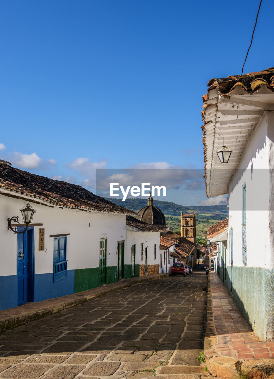 HOUSES BY STREET IN TOWN AGAINST BLUE SKY