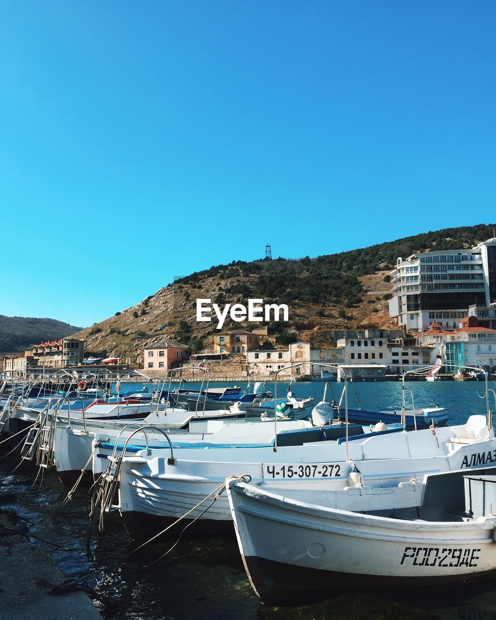 BOATS MOORED IN HARBOR AGAINST BUILDINGS