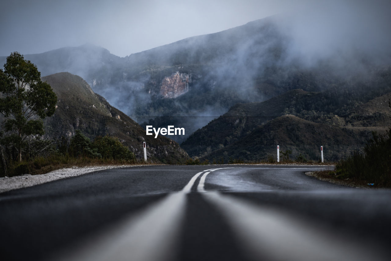 Road leading towards mountains against sky