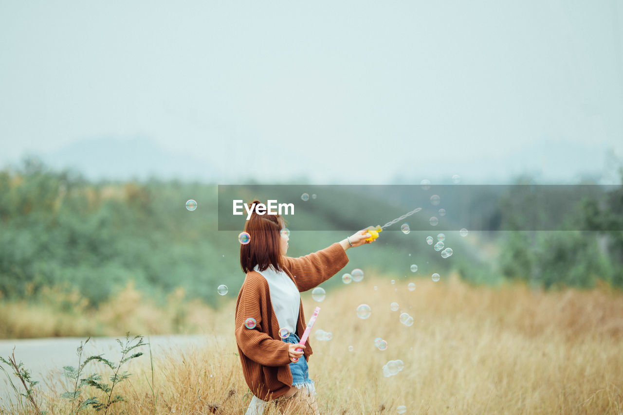 Woman playing with bubbles on field