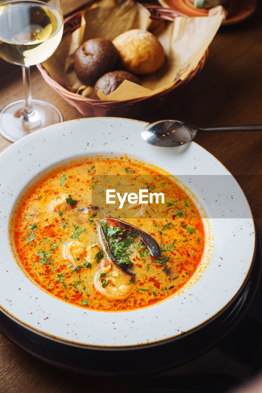 From above of appetizing aromatic tomato soup with porcini mushrooms and green herbs served on white plate