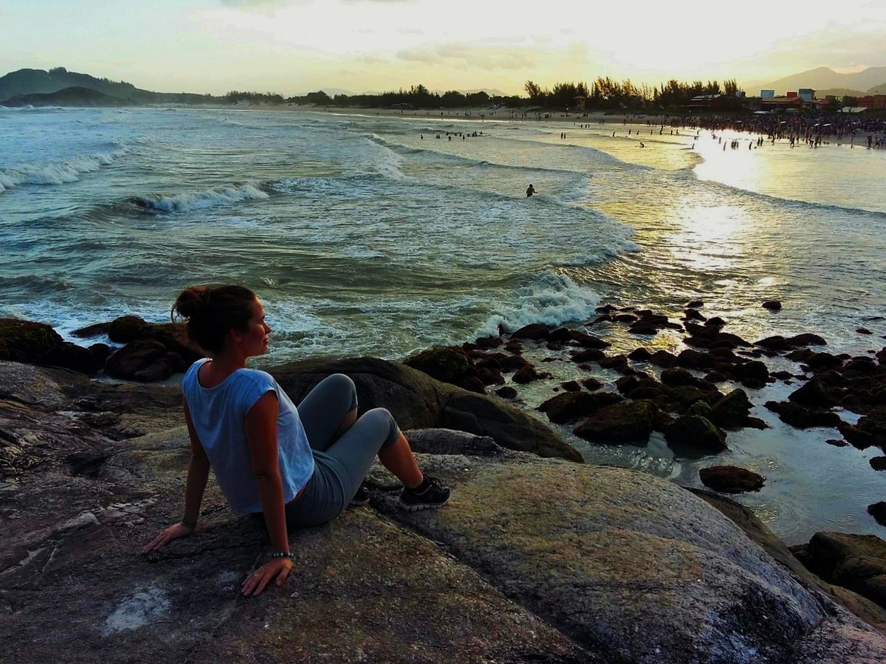 Full length of woman relaxing on rock at beach during sunset