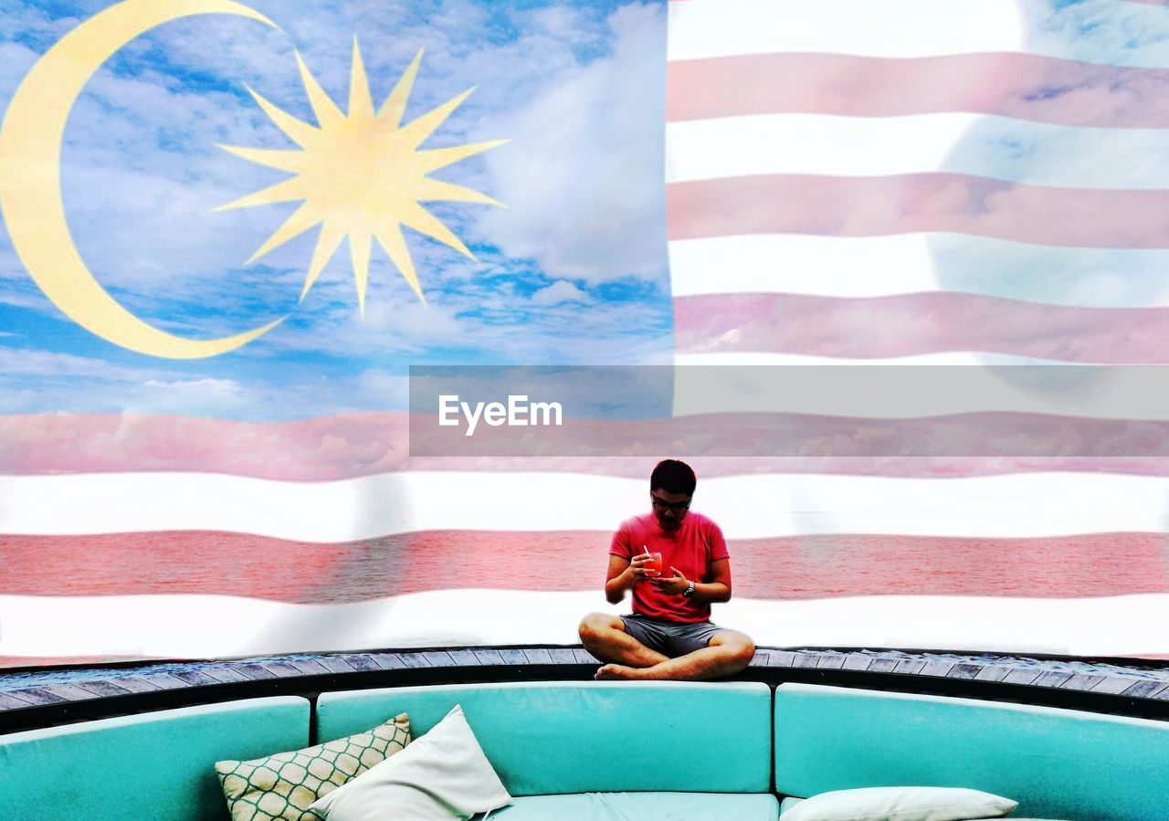 Man sitting against malaysian flag painting