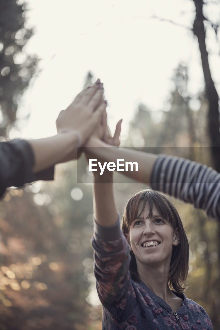 Smiling females doing high five outdoors