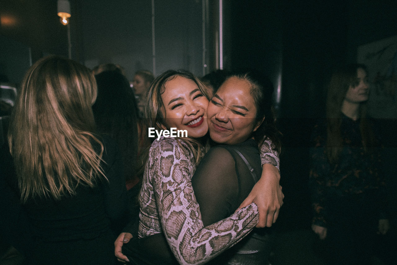 Cheerful young women embracing each other while enjoying at nightclub