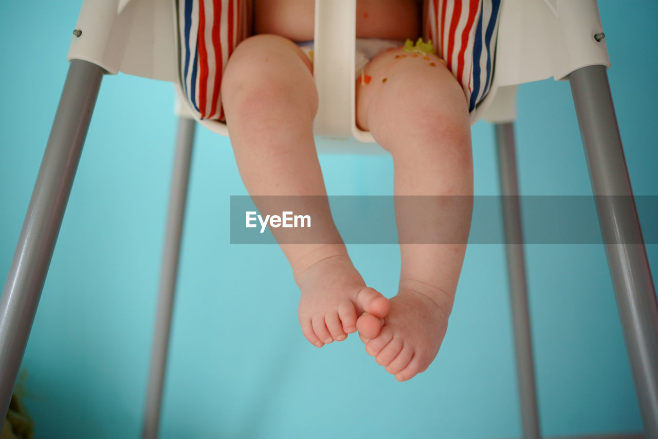 The child eats in a child seat, his legs are visible