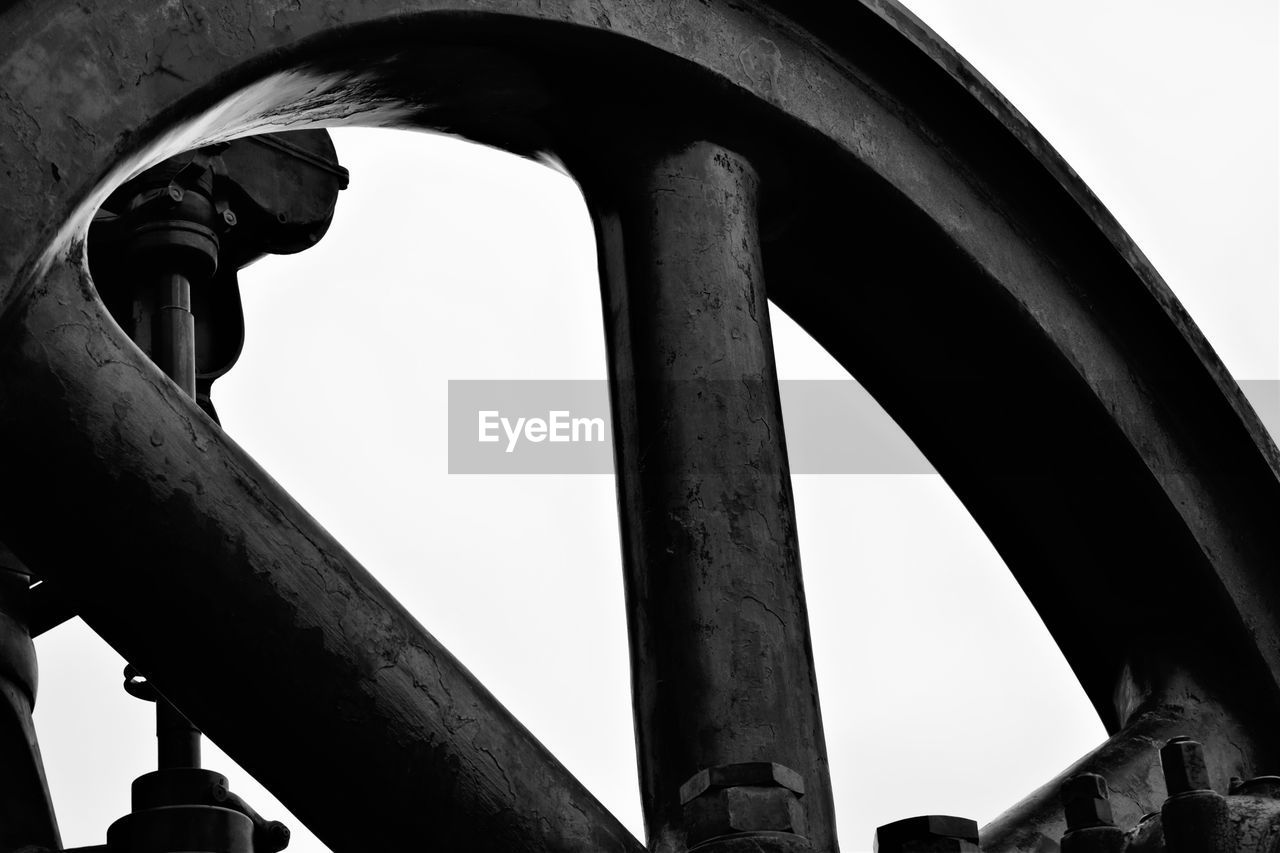 Low angle view of metal wheel against clear sky