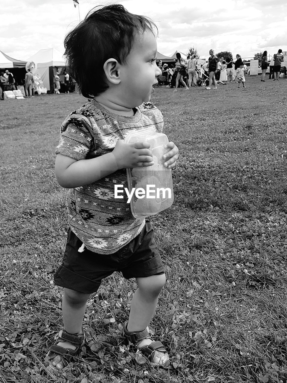 Cute baby boys standing on field against sky