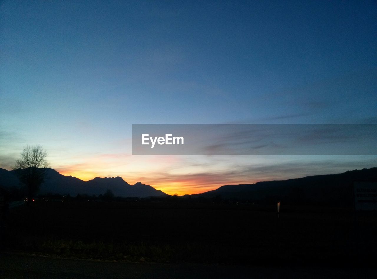 Scenic view of mountains against blue sky during sunset