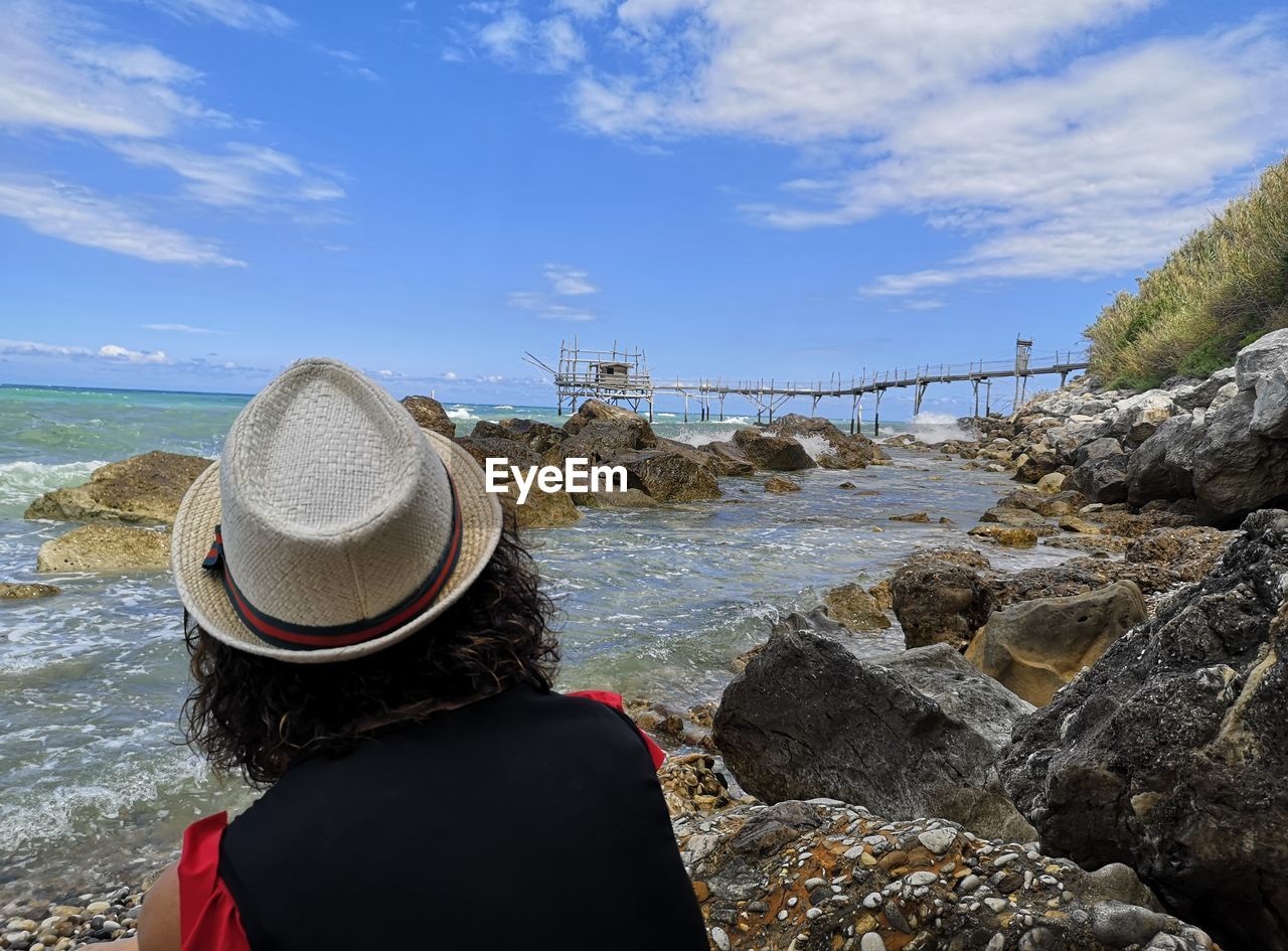REAR VIEW OF WOMAN LOOKING AT SEA SHORE