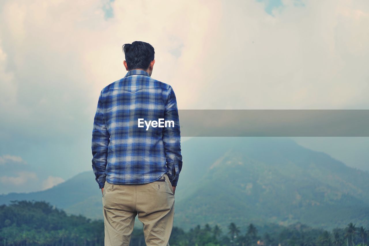 Rear view of man looking at mountain against sky