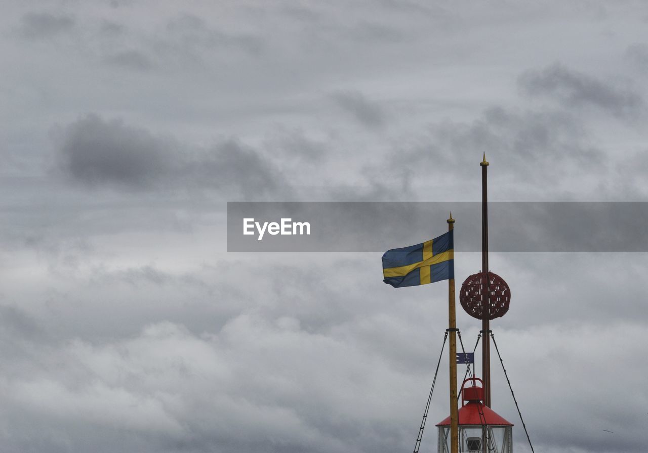 Low angle view of crane against cloudy sky