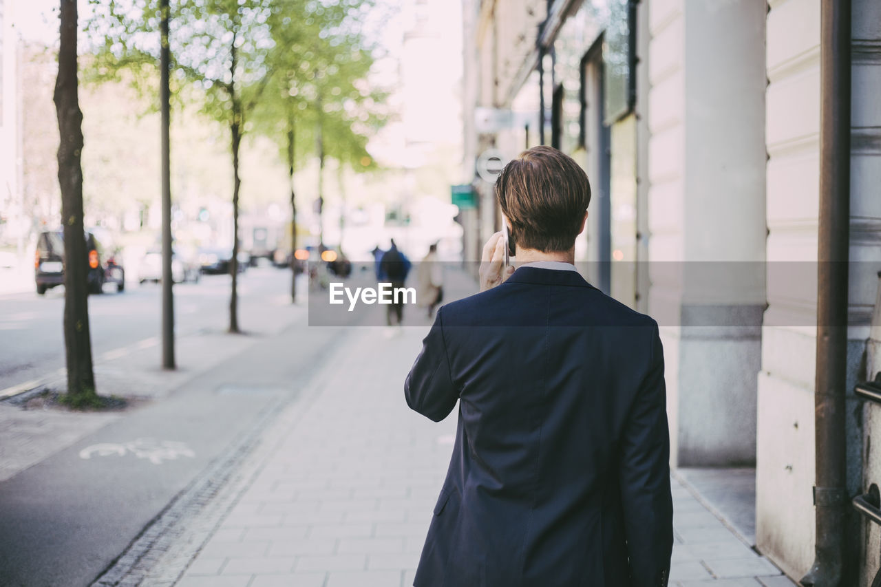 Rear view of businessman talking on phone in city