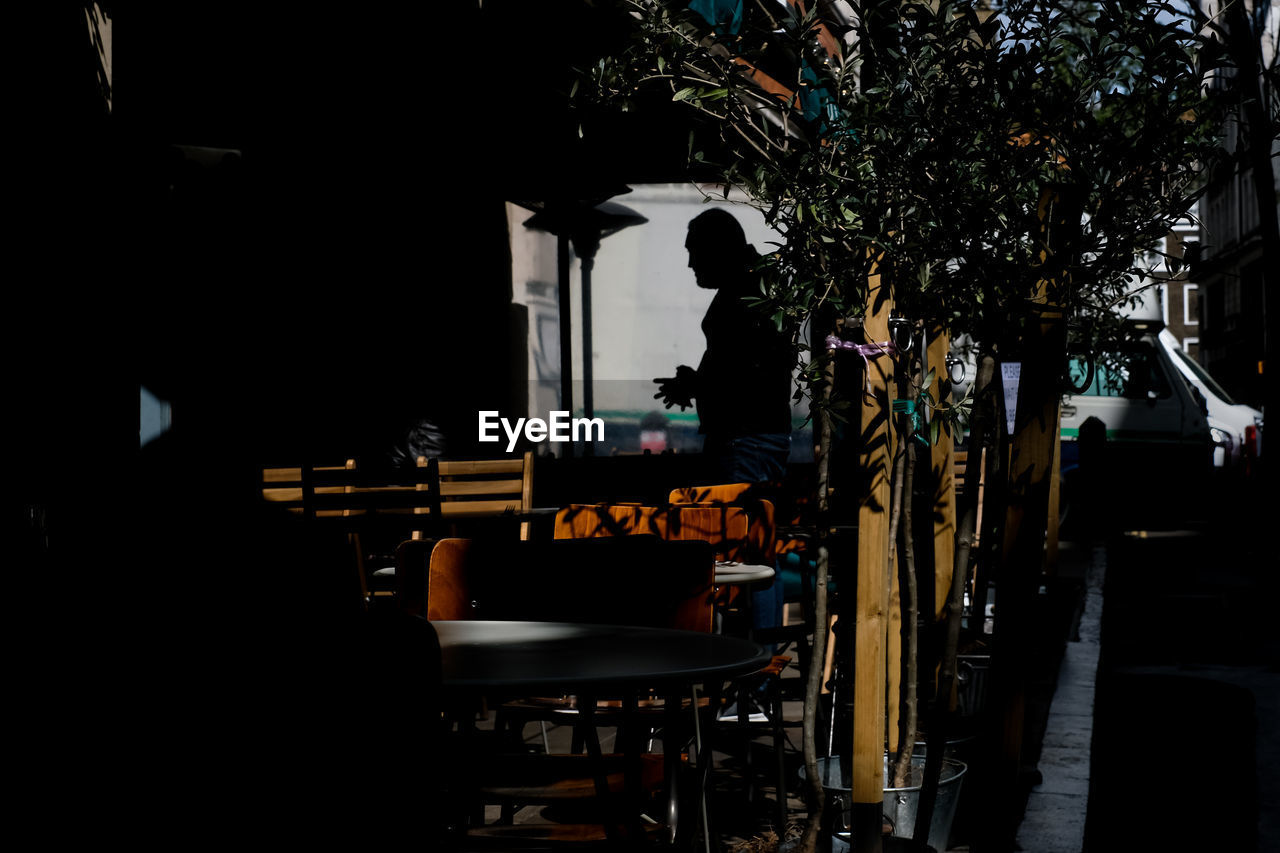 Silhouette of standing man and empty chairs in restaurant