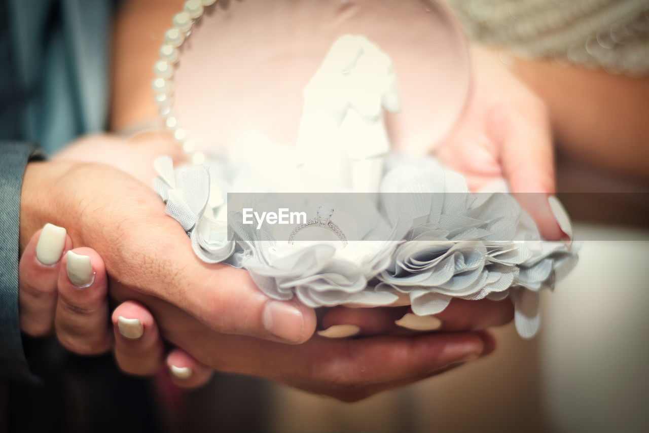 Close-up of couple holding ring during wedding ceremony