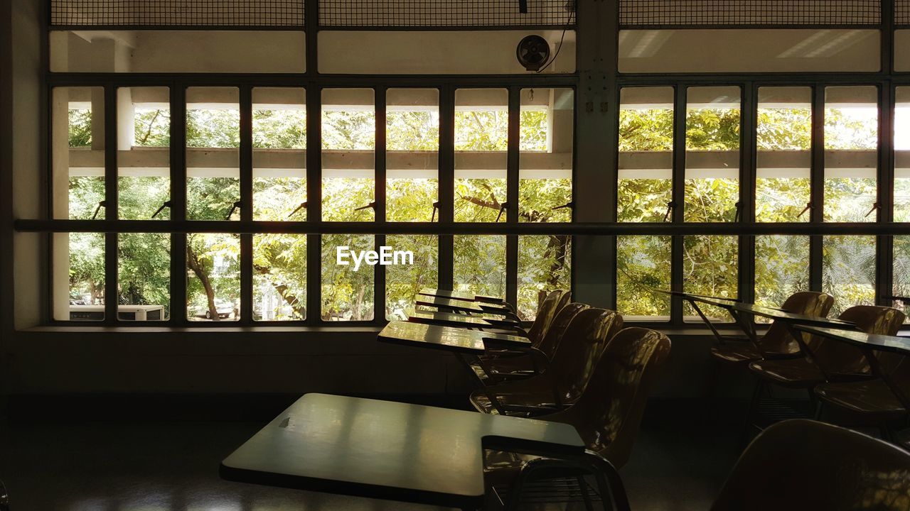 Empty chairs and desks by windows in classroom