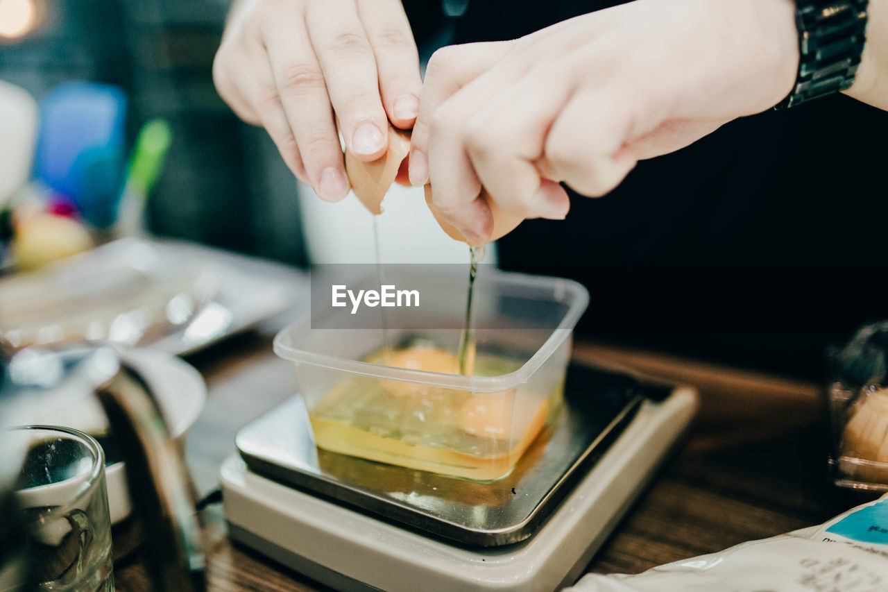 Midsection of woman breaking eggs in bowl on table