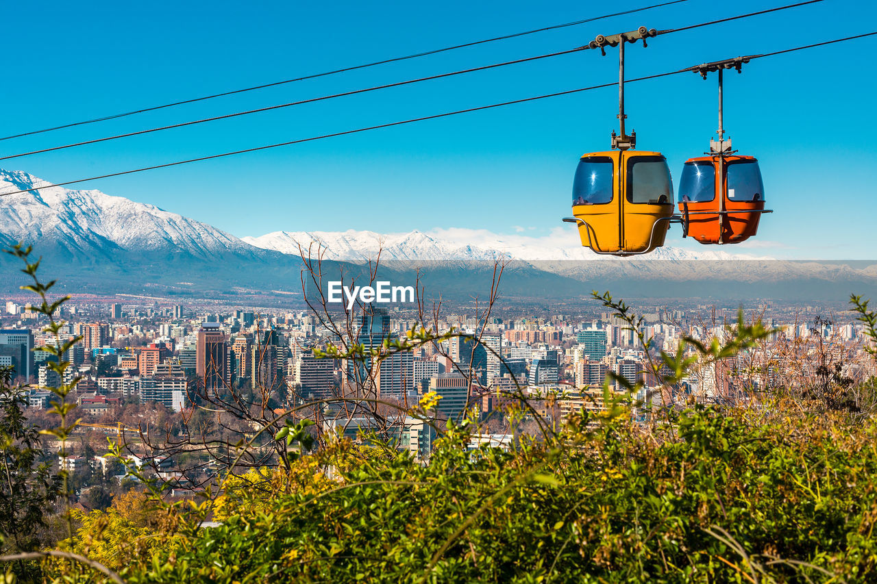 Overhead cable cars against sky in city