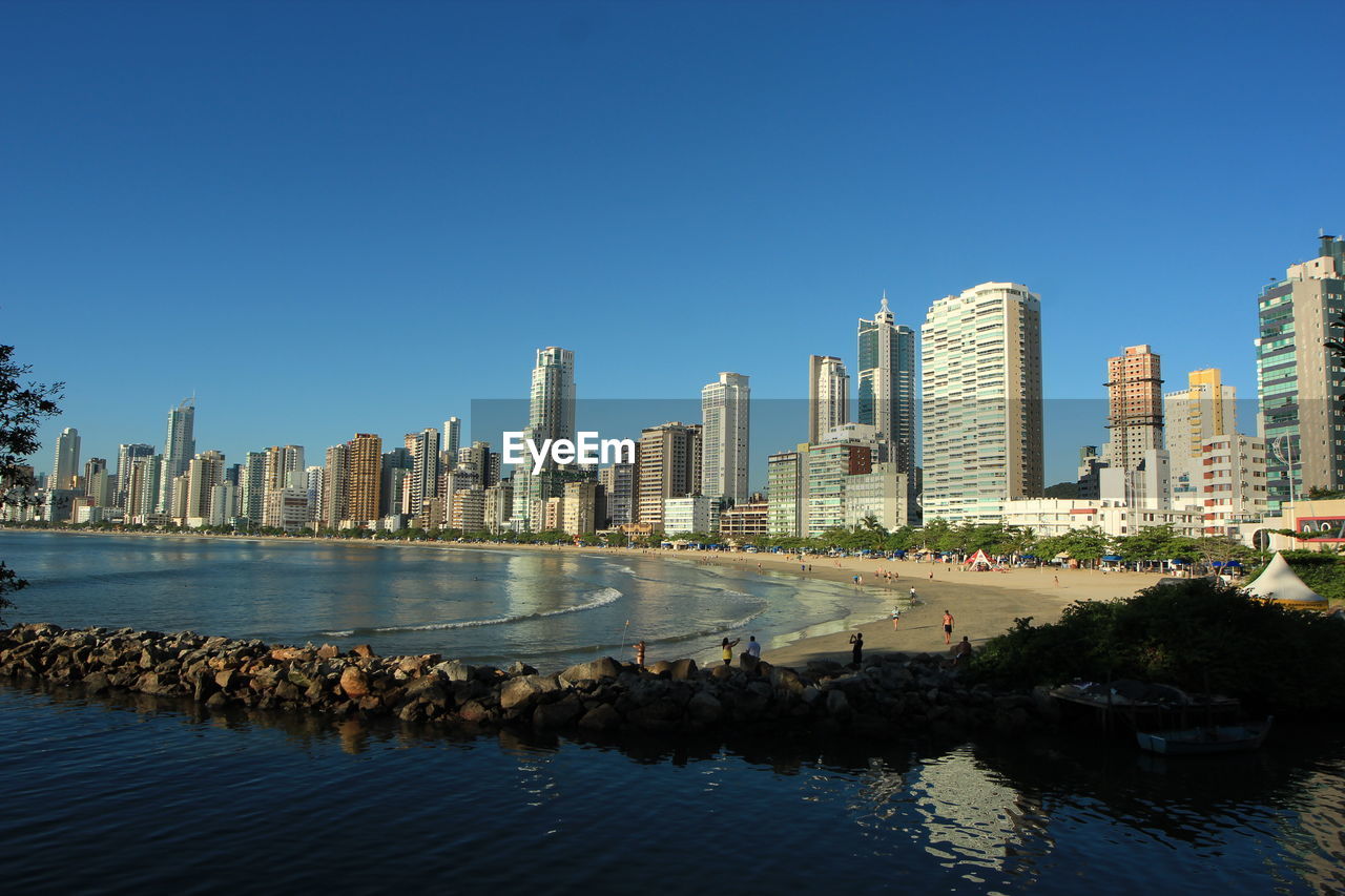 Cityscape by sea against clear sky