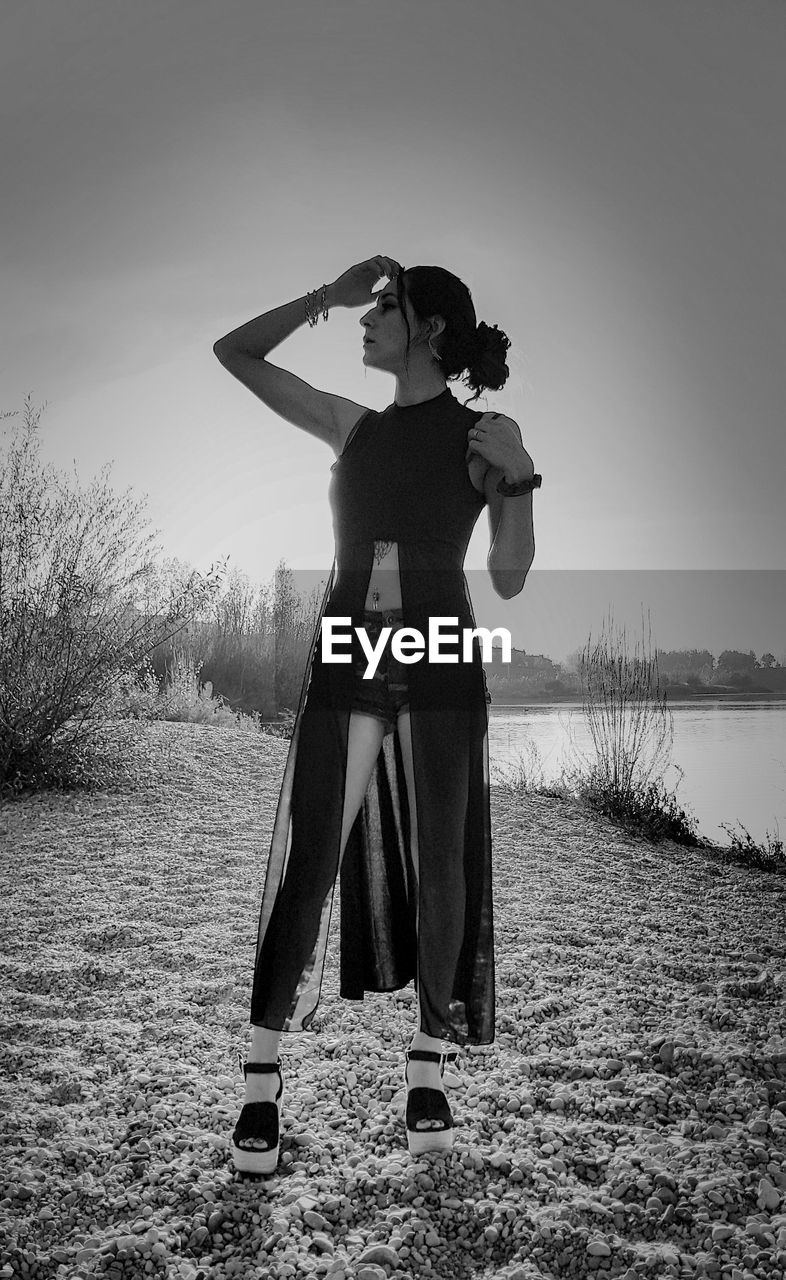 Woman standing at lakeshore against clear sky