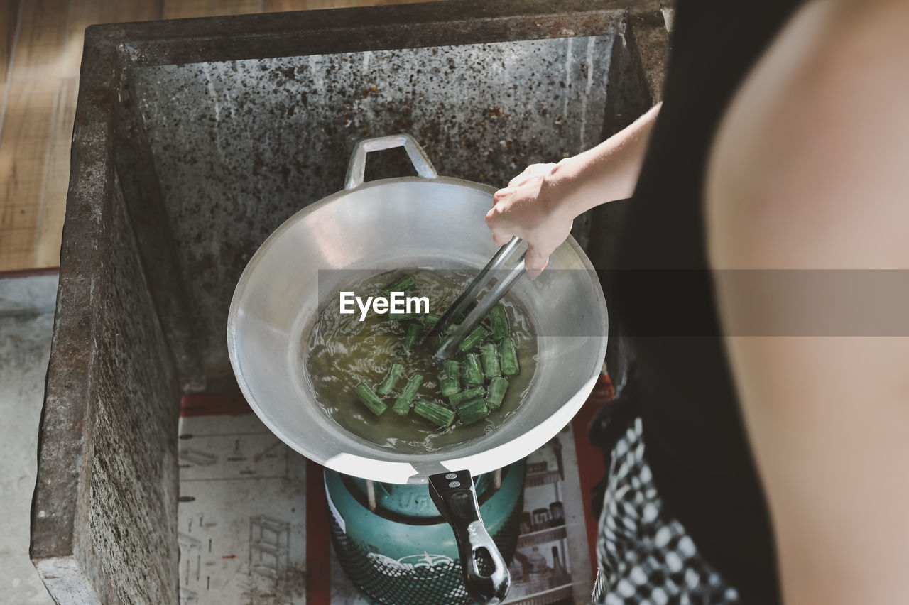 Human part ,woman cooking green vegetable in frying pan