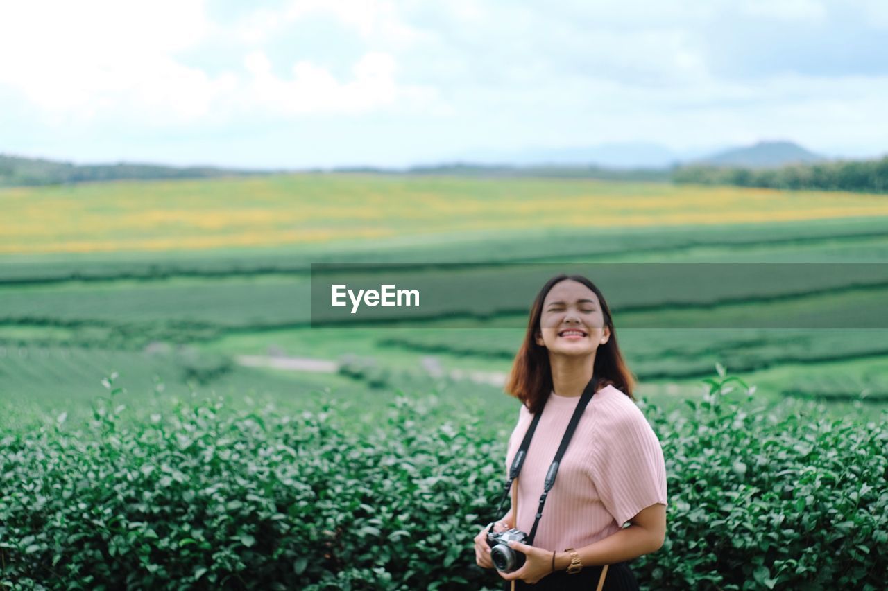 Young woman standing against agricultural field