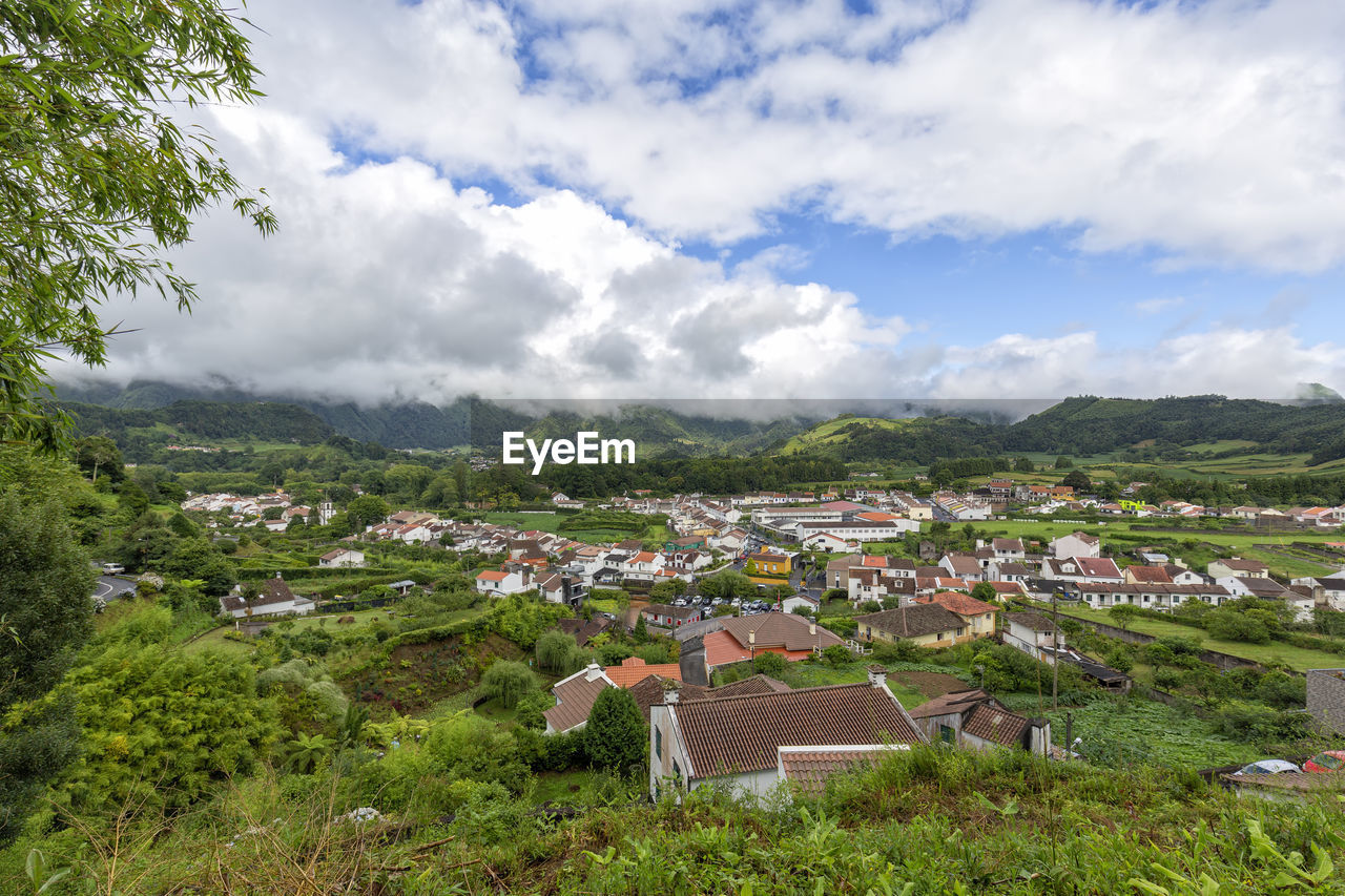 HIGH ANGLE VIEW OF TOWNSCAPE BY TREES AGAINST SKY