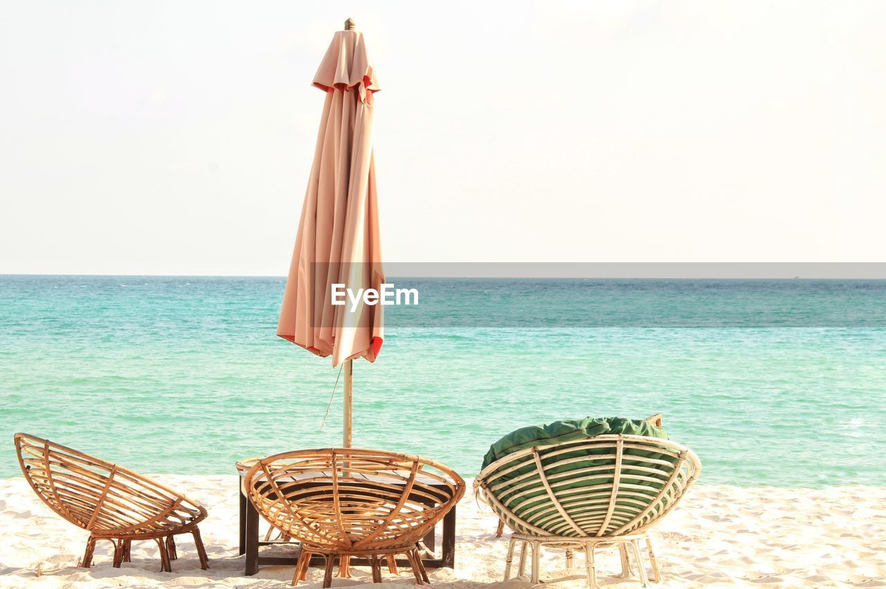 Deck chairs on beach against clear sky