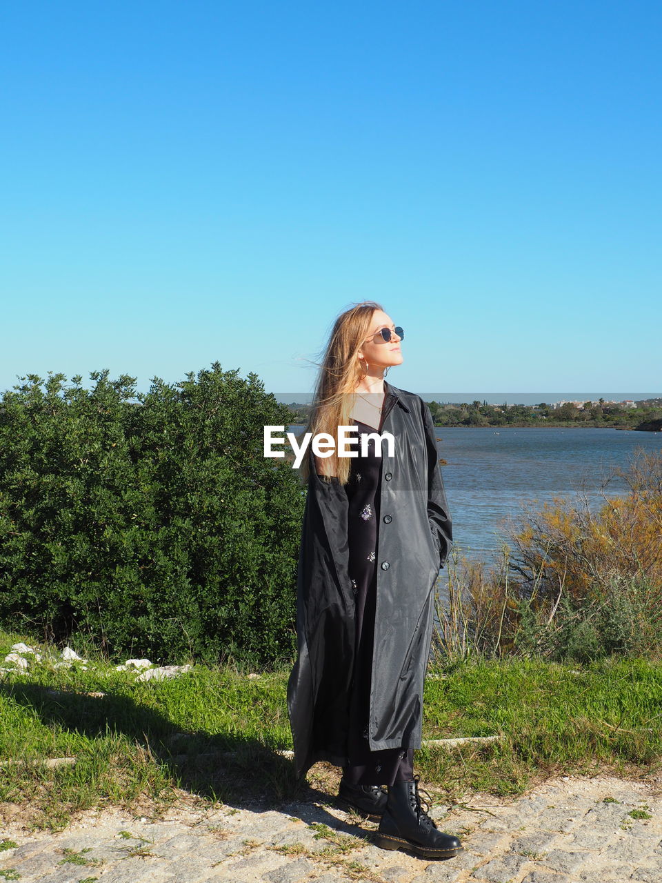 Woman standing by plants against clear sky