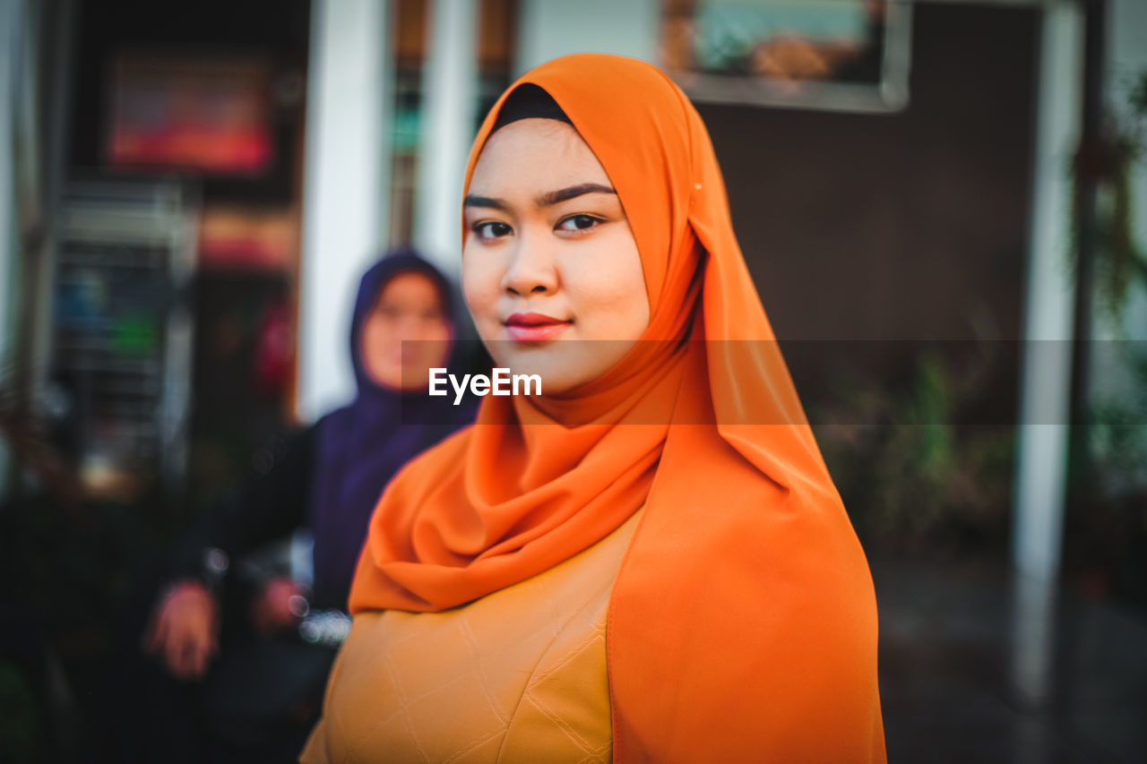 Portrait of smiling young woman in headscarf standing outdoors