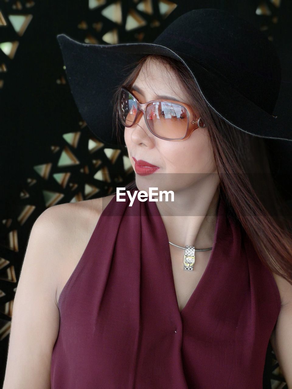 Fashionable woman wearing sunglasses and hat looking away