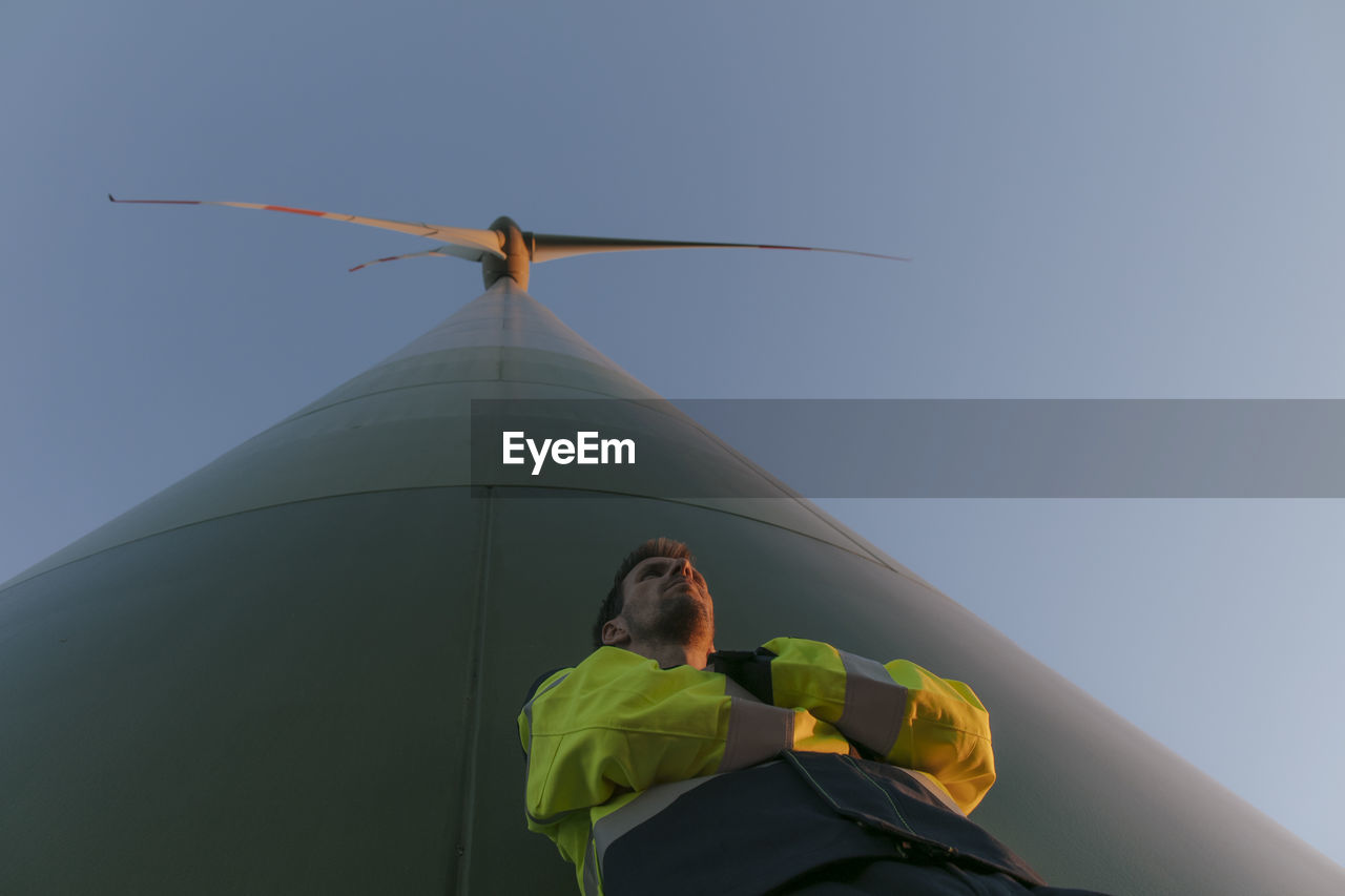 Low angle view of engineer standing at a wind turbine