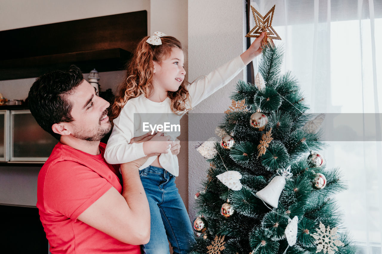 Happy father and daughter decorating christmas tree