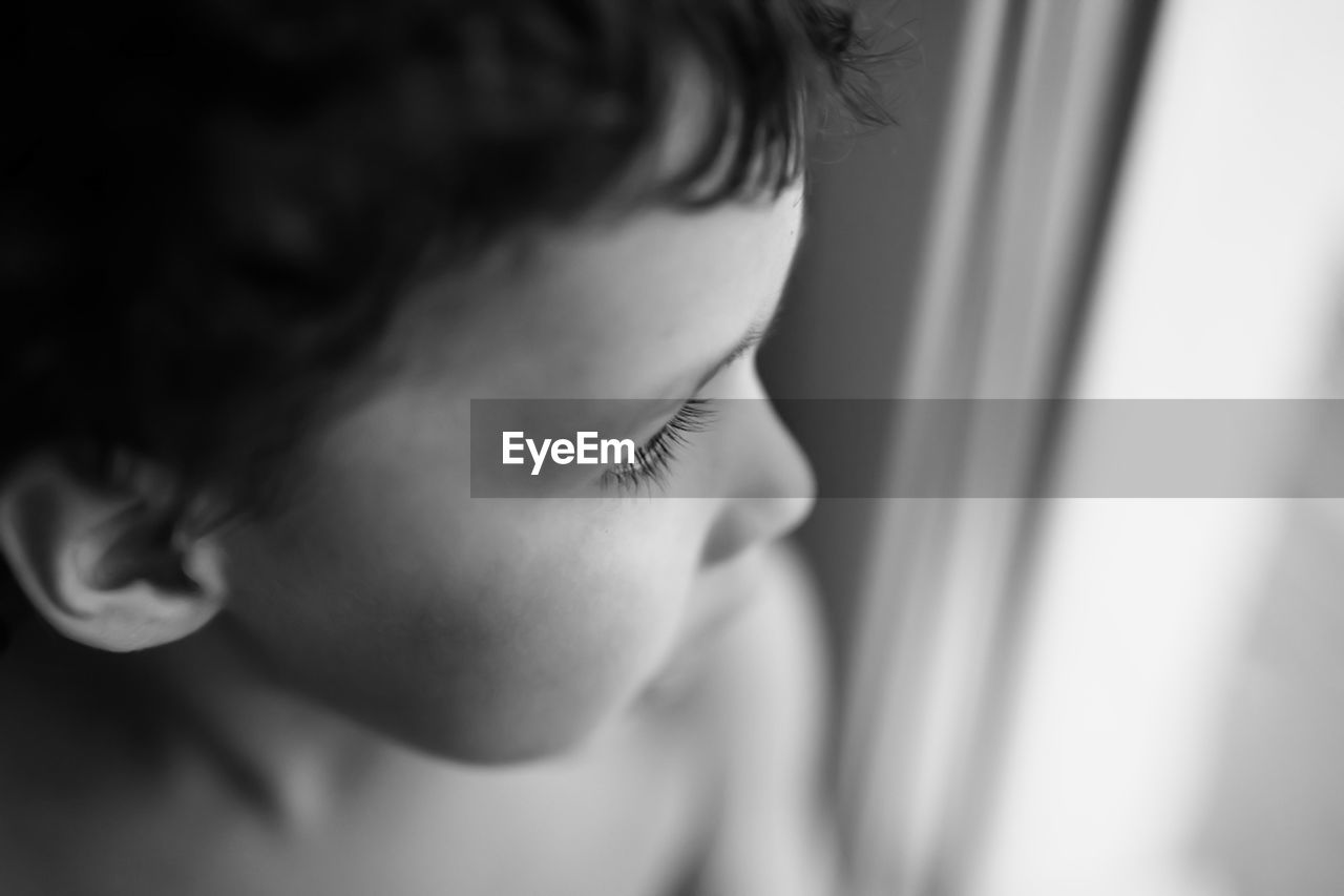 Close-up of boy looking through window