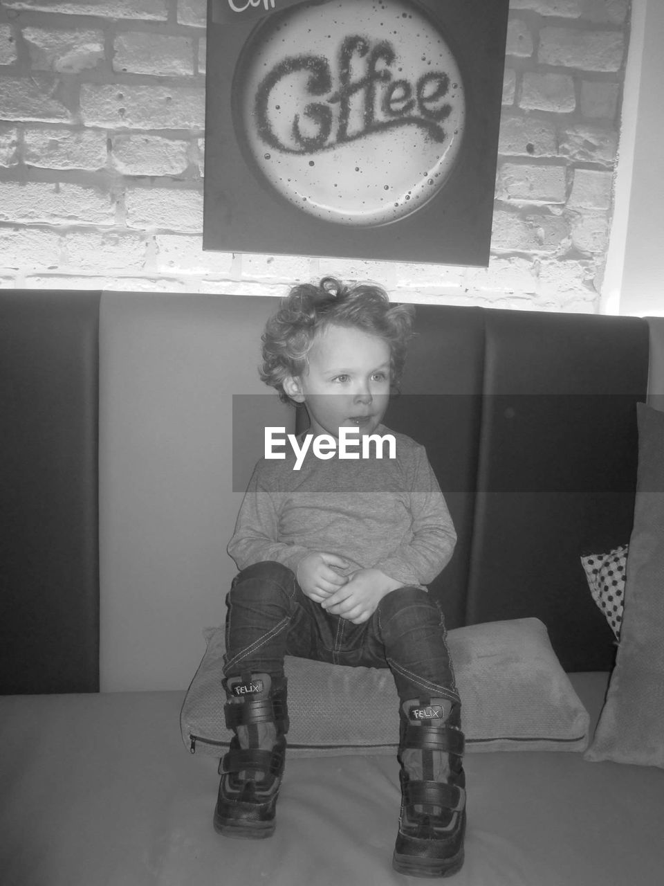 Cute boy sitting on cushion at cafe