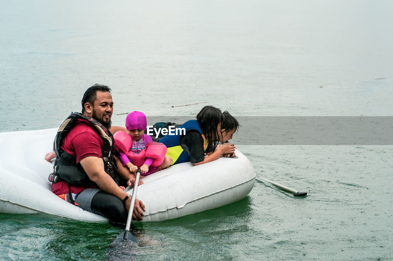 Family wearing life jackets paddling on an inflatable boat in a lake