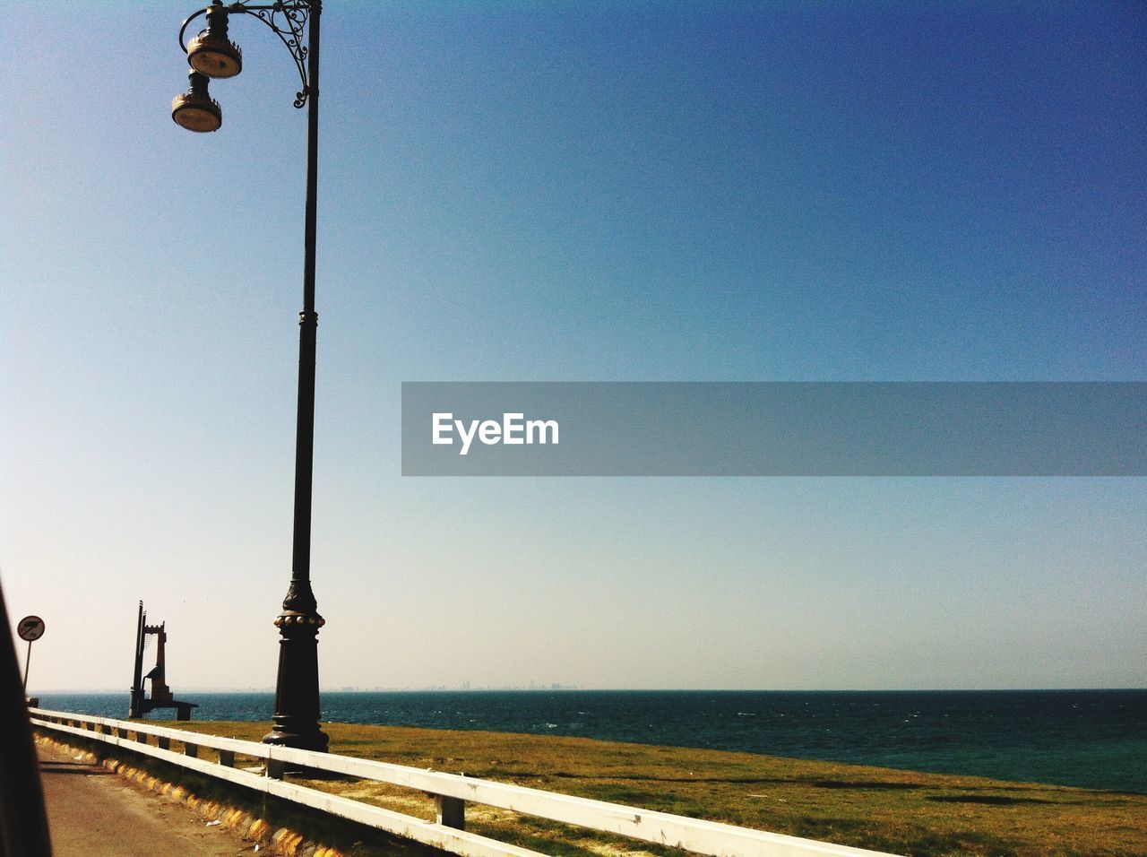 STREET LIGHTS BY SEA AGAINST CLEAR SKY