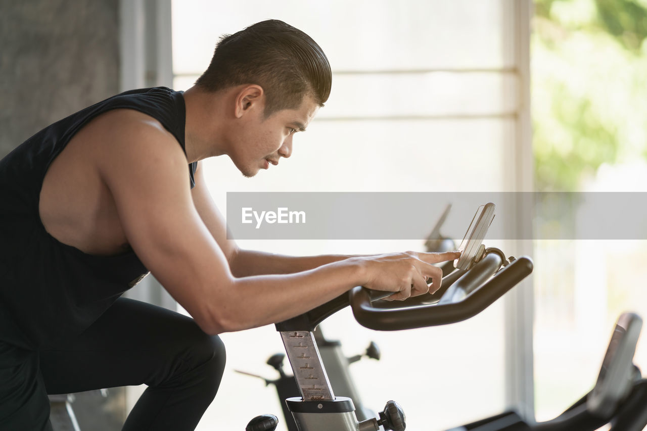 Side view of young man exercising at gym