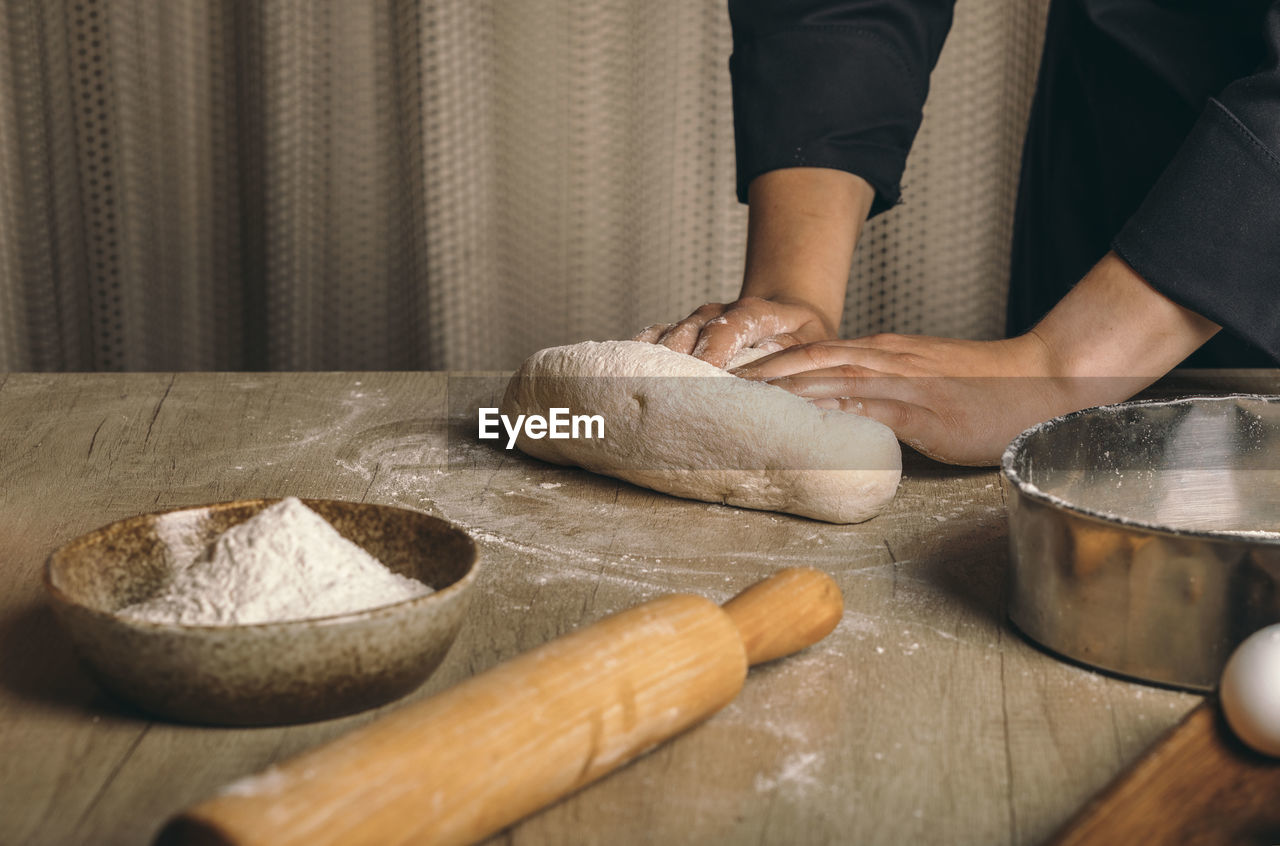 A woman kneads the dough with flour close-up. the cook prepares bread dough