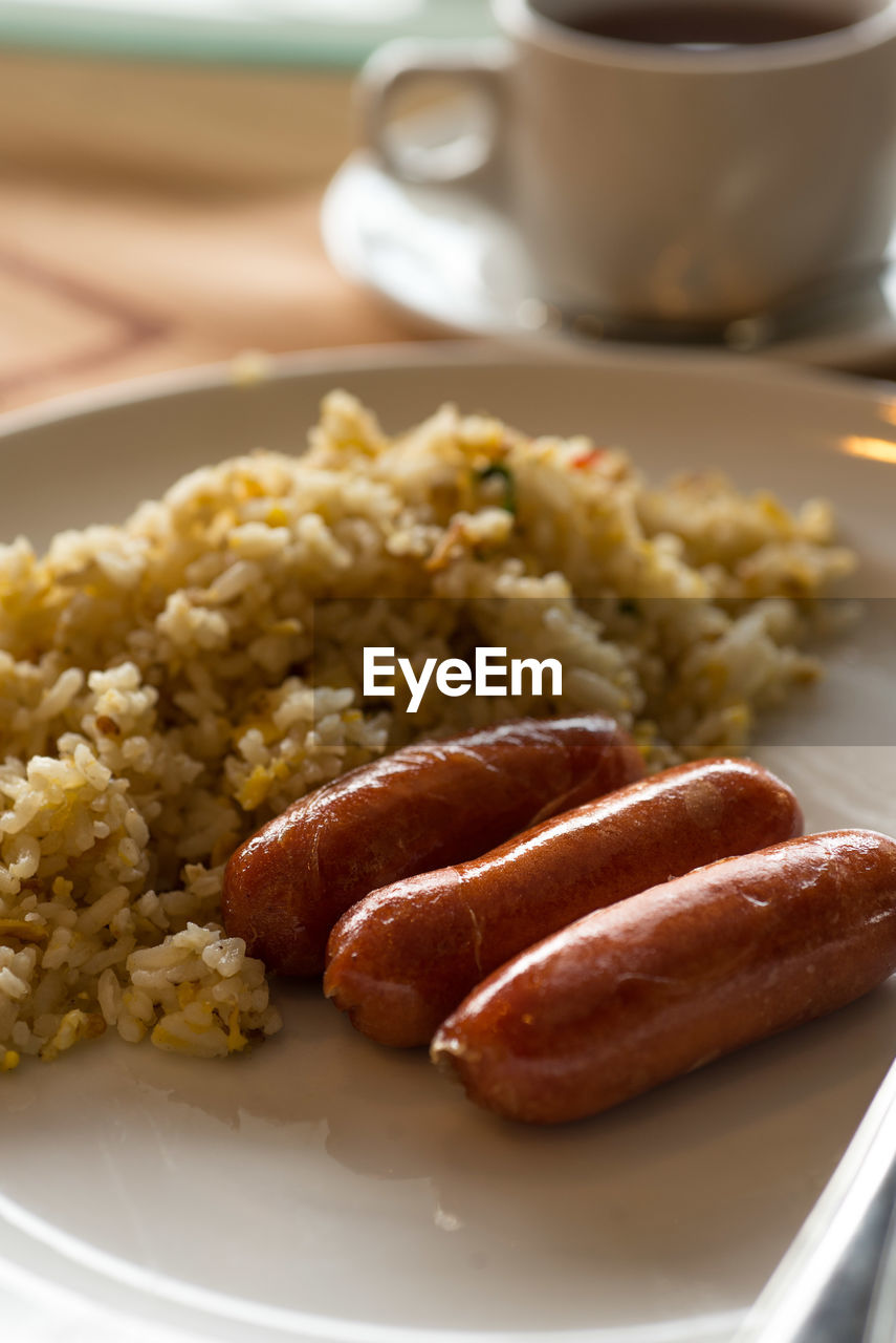 High angle close-up of sausages with rice served in plate on table