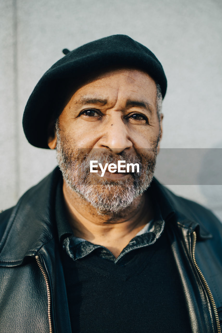 Portrait of senior man with flat cap against wall