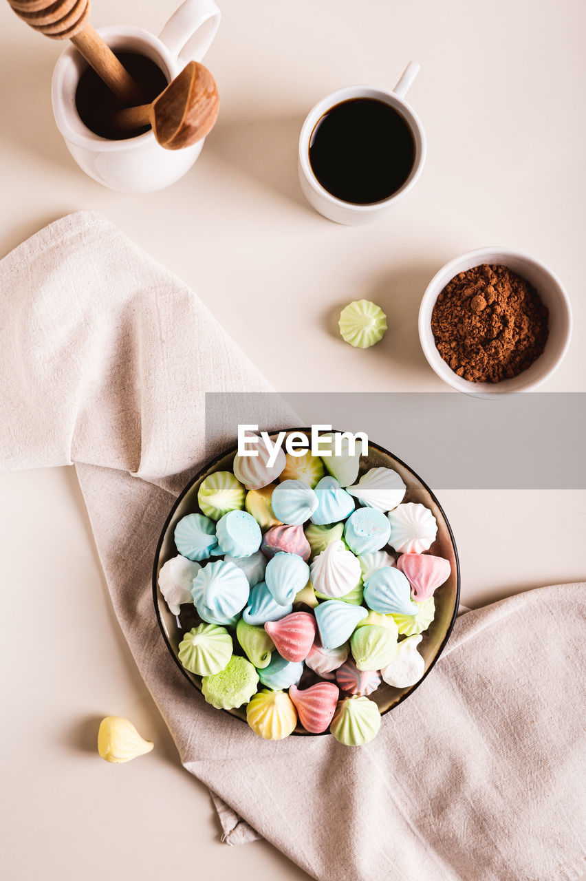 Sweet small meringues for dessert on a plate on the table top and vertical view