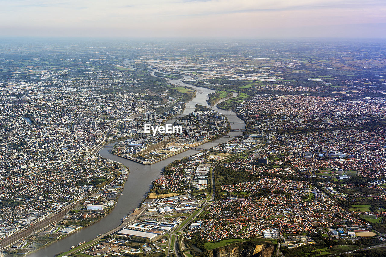 AERIAL VIEW OF CITY BY RIVER AGAINST SKY