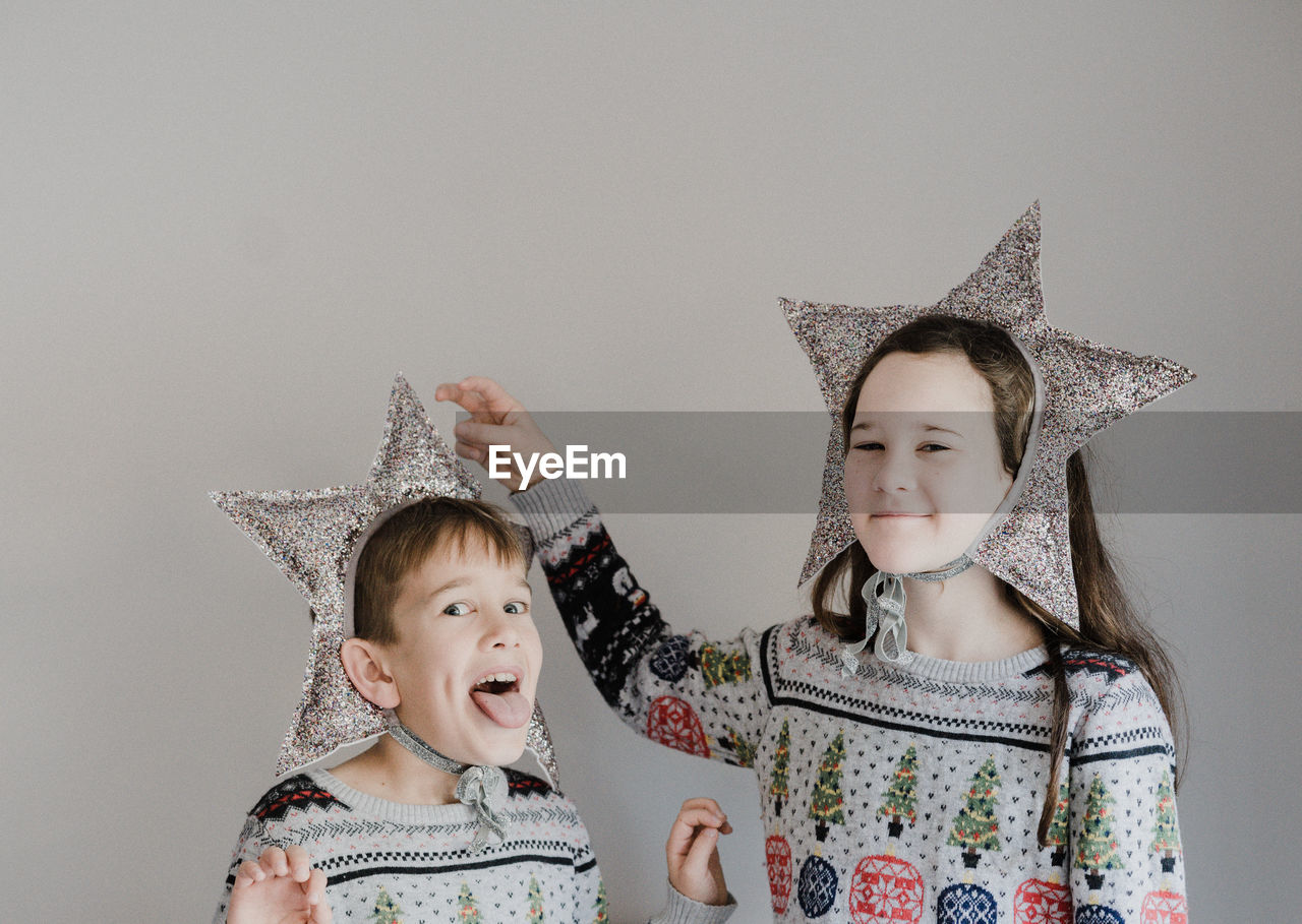 Portrait of siblings wearing star shape decorations against white background